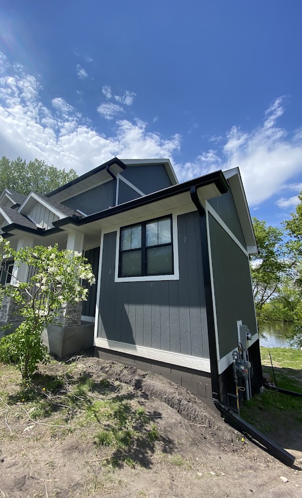 Black seamless gutters and downspouts installed on a lake home